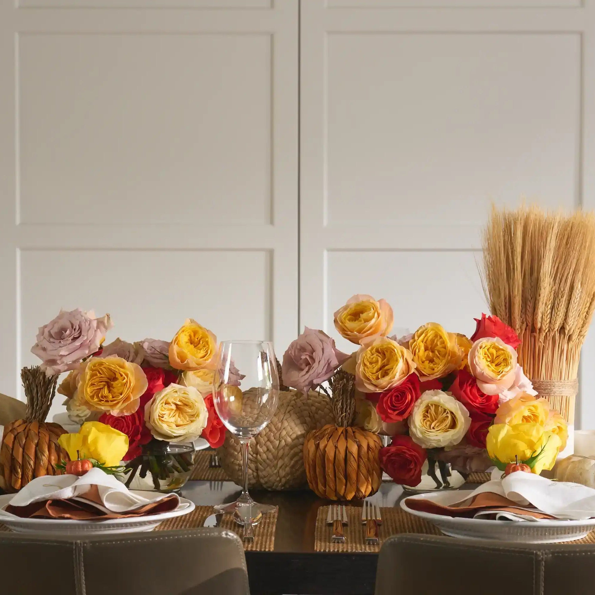 Decorative table setting with flowers, pumpkins, and glasses in a kitchen.