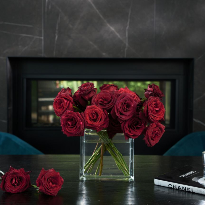 Bouquet of red roses in a clear vase on a table with a blurred background