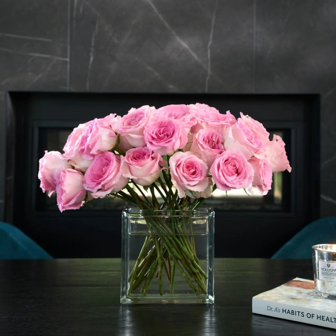 Bouquet of pink roses in a clear vase on a table with a dark background
