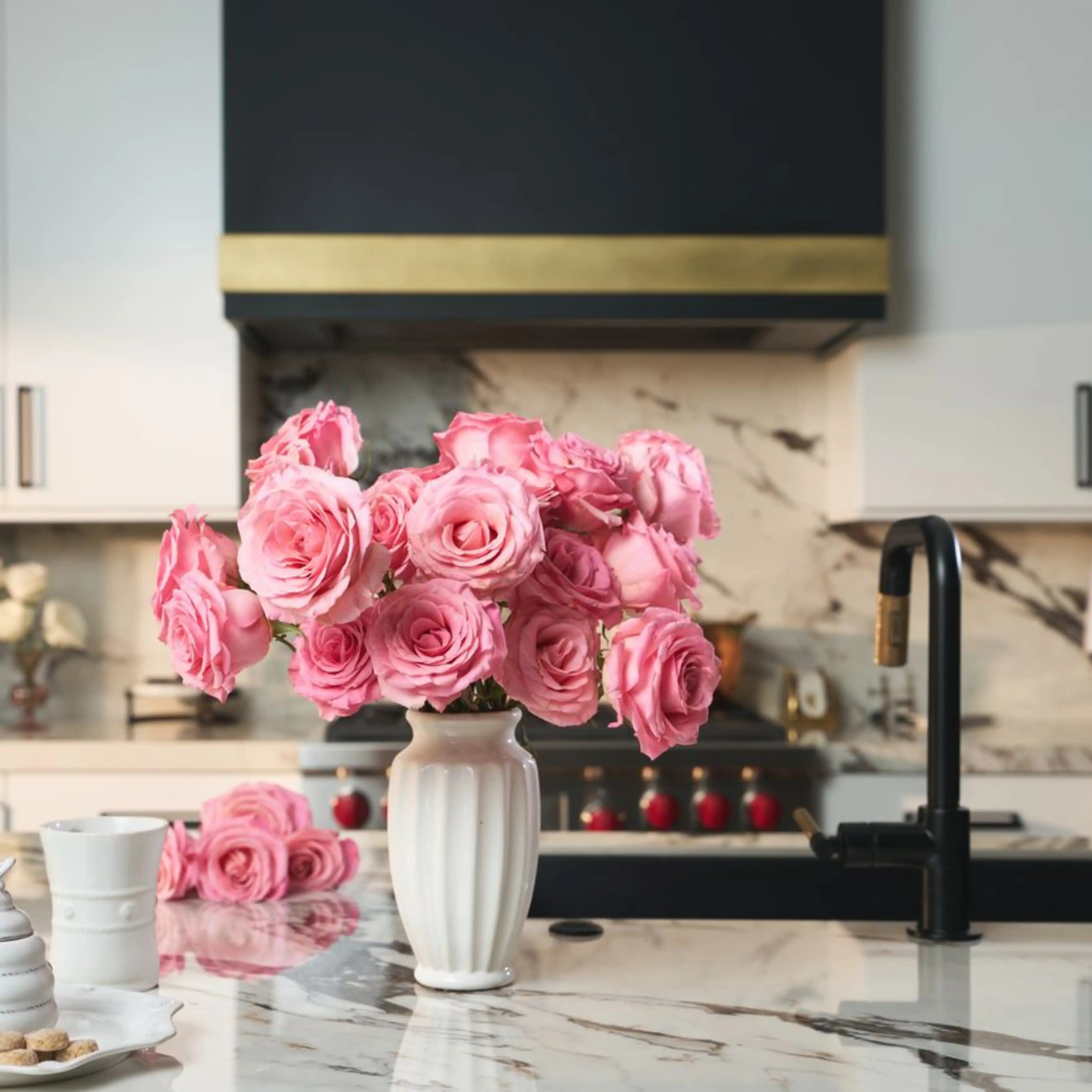 Bouquet of pink roses in a white vase on a kitchen counter.