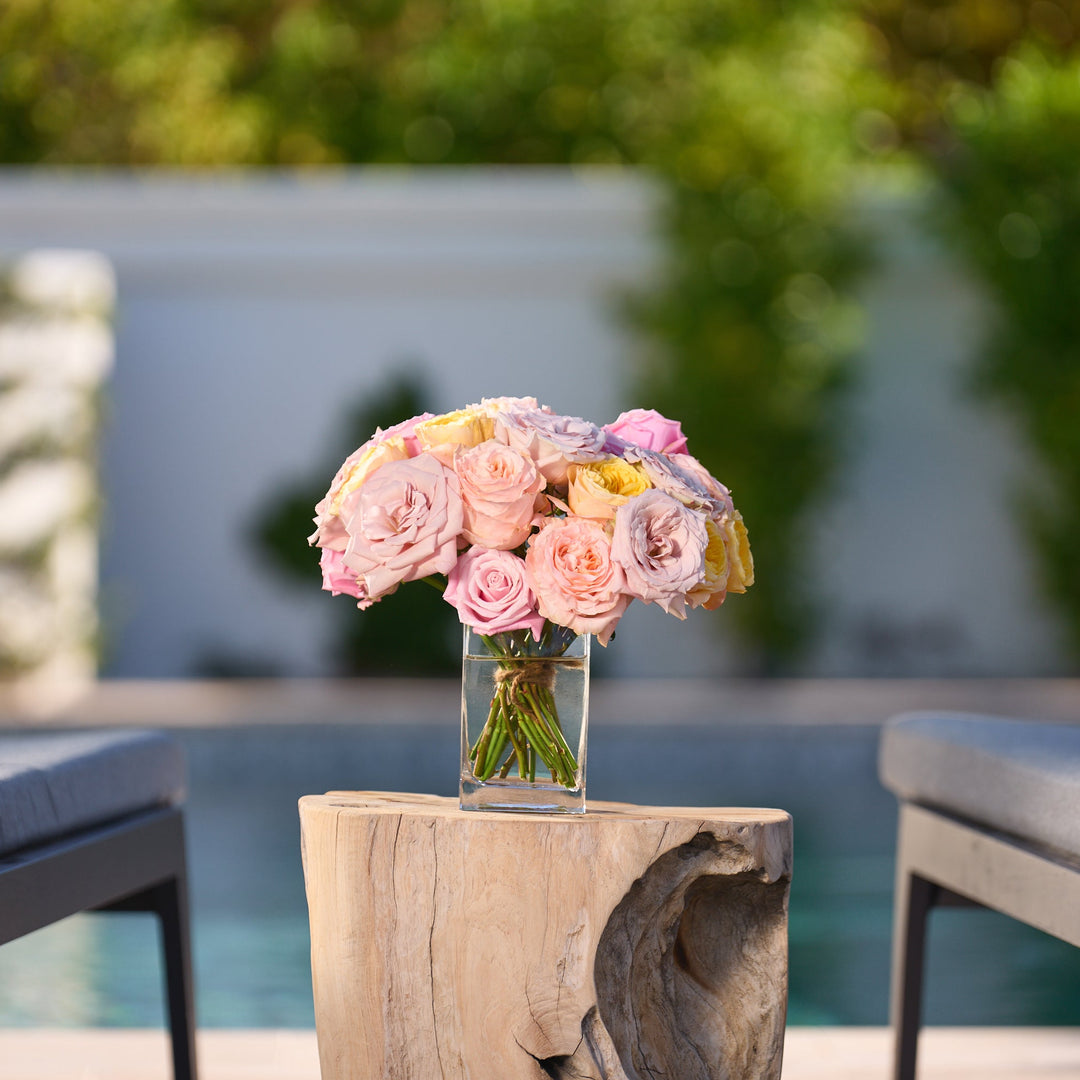 Bouquet of flowers on a wooden table with chairs and a pool in the background