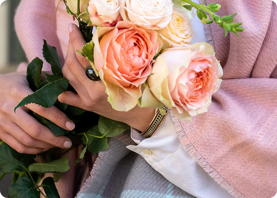 Person holding a bouquet of pink and white roses with a blurred background