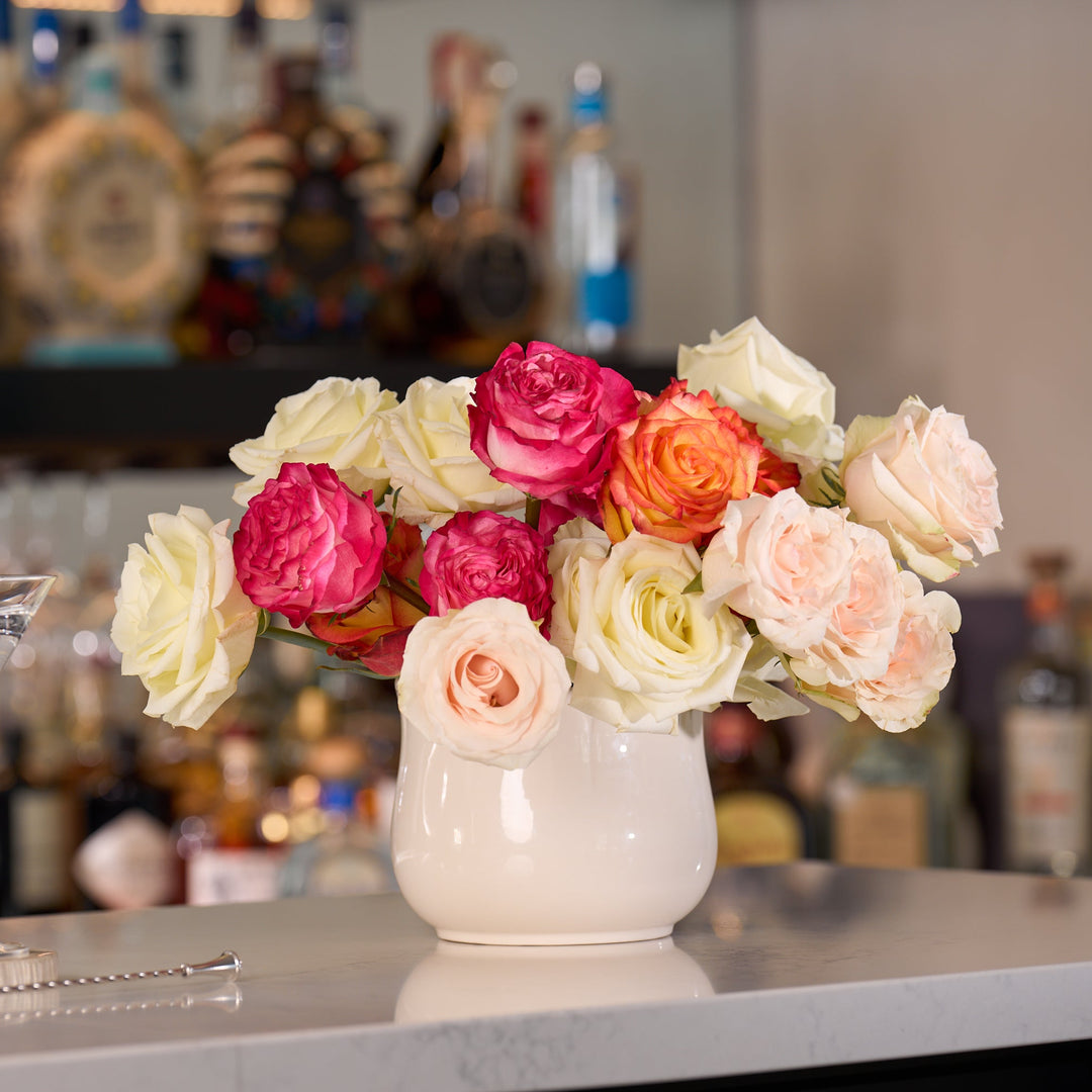Bouquet of flowers in a vase on a bar counter with a cocktail shaker and glass.