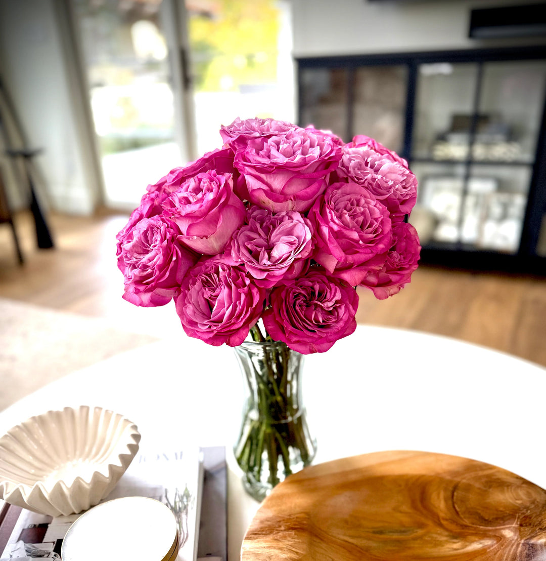 Bouquet of pink roses in a clear vase on a table with a blurred background
